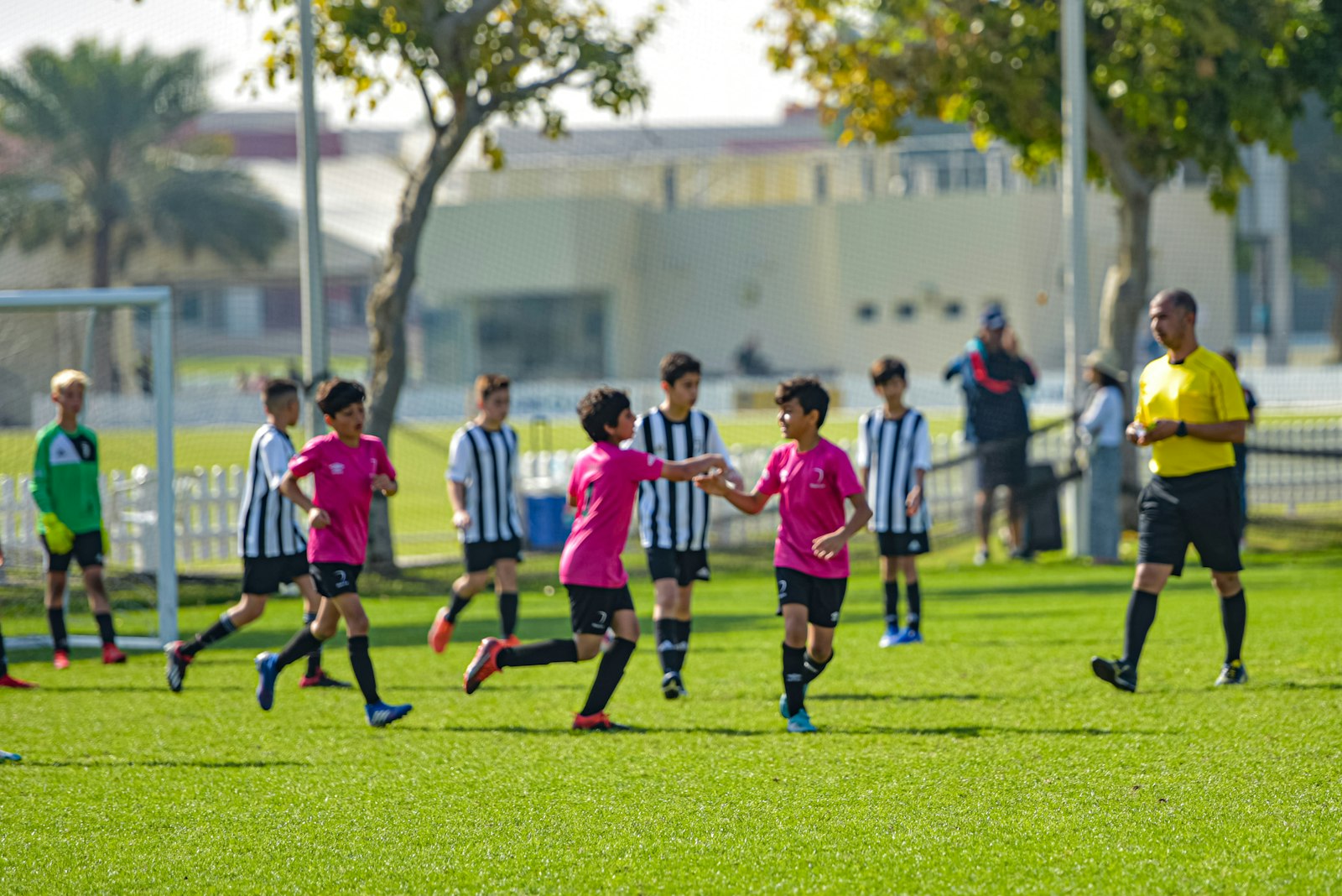 Kids in red and white uniforms playing soccer on a green grass field